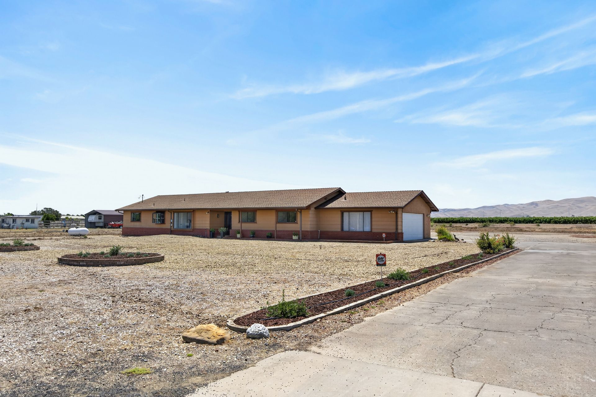 Front elevation of the single-story ranch home set against open ground with the Diablo Range rising softly in the distance