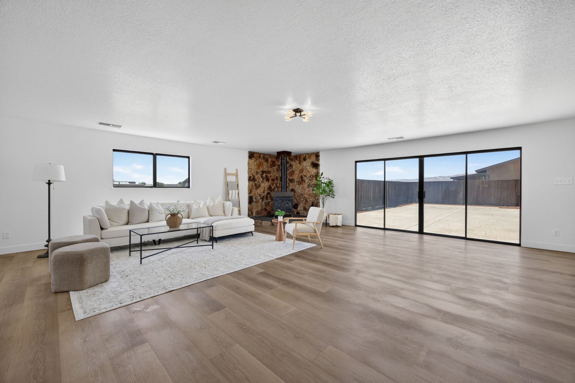 Family room looking out to the patio through a wall of sliding glass, with the stone fireplace anchoring the right side