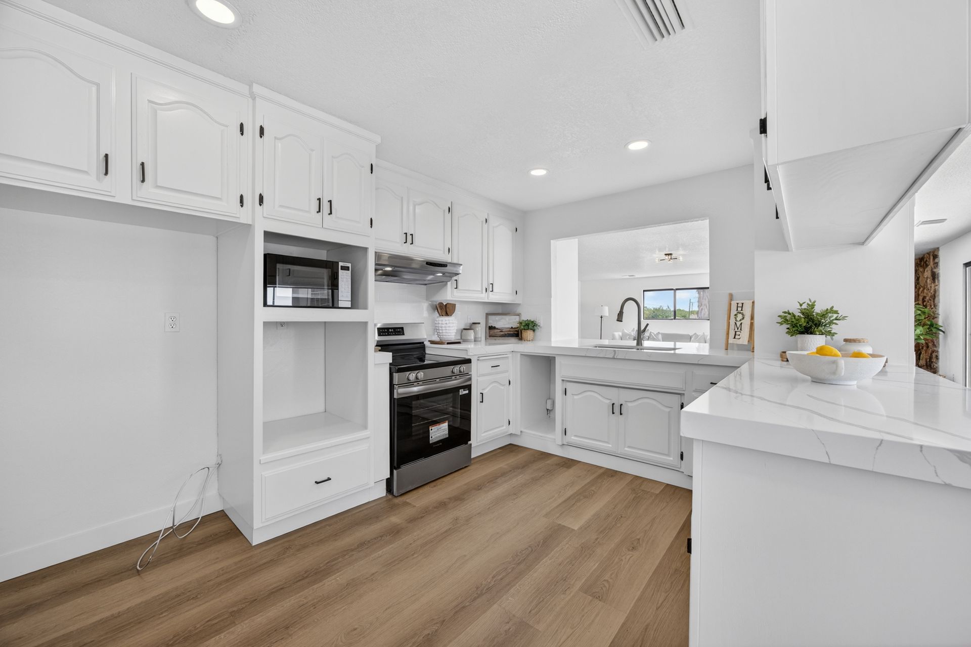 Wide view of the kitchen showing the full run of cabinetry, the gas range, and the breakfast bar countertop