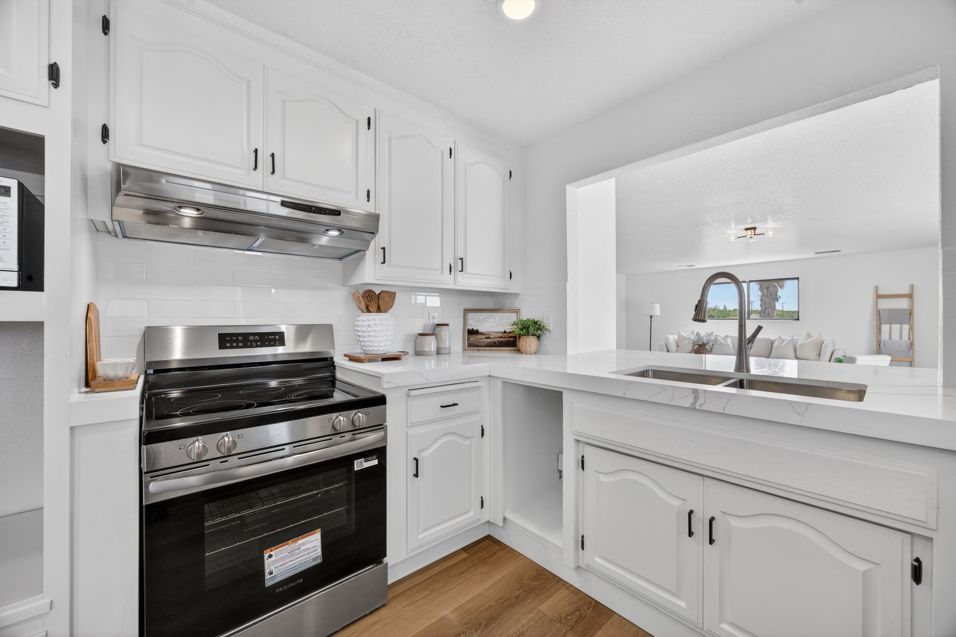 Detail of the kitchen showing the stainless range hood, range, and quartz waterfall countertop