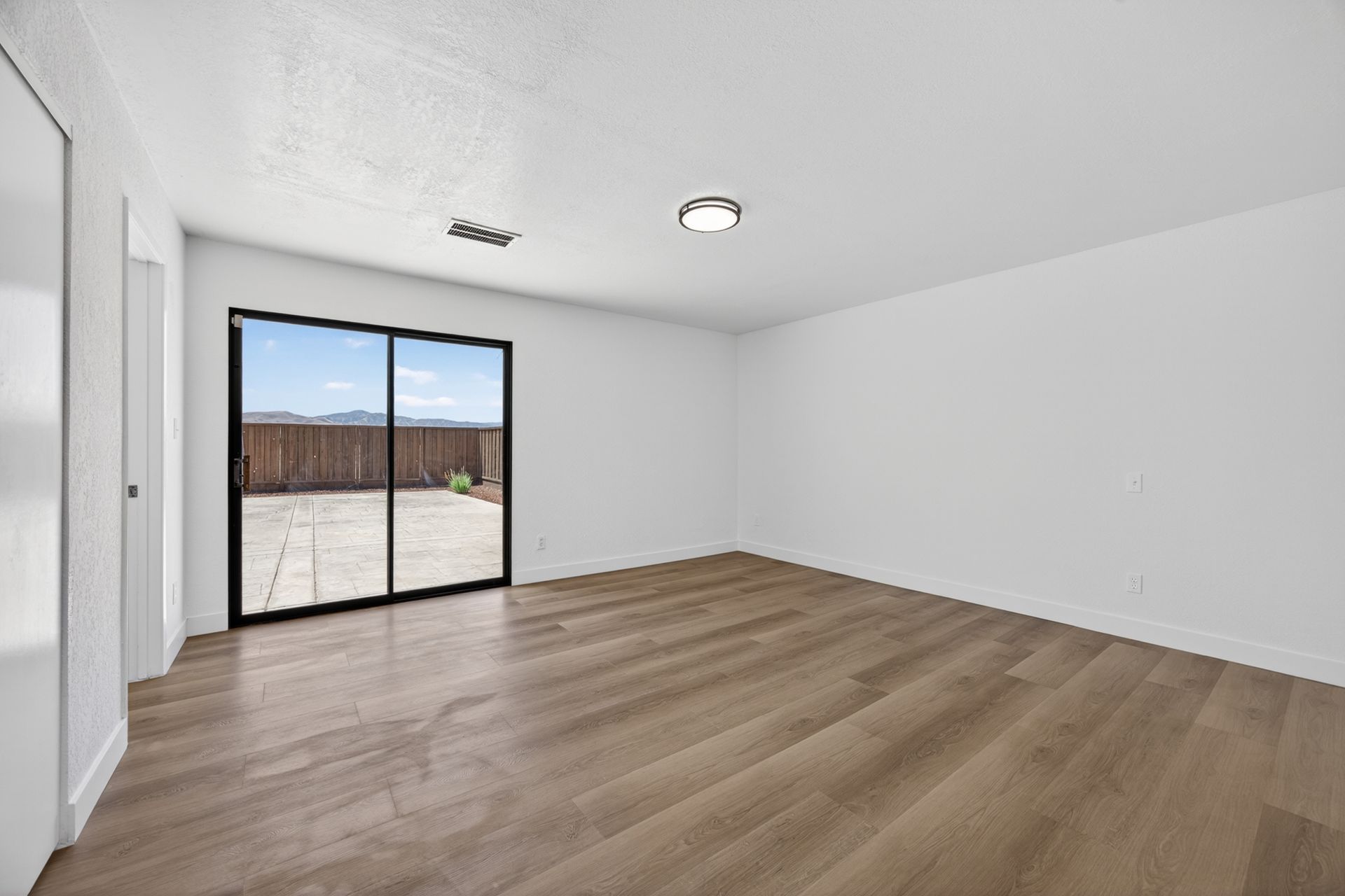 A bedroom with sliding glass doors leading to the patio and an unobstructed view to the hills beyond