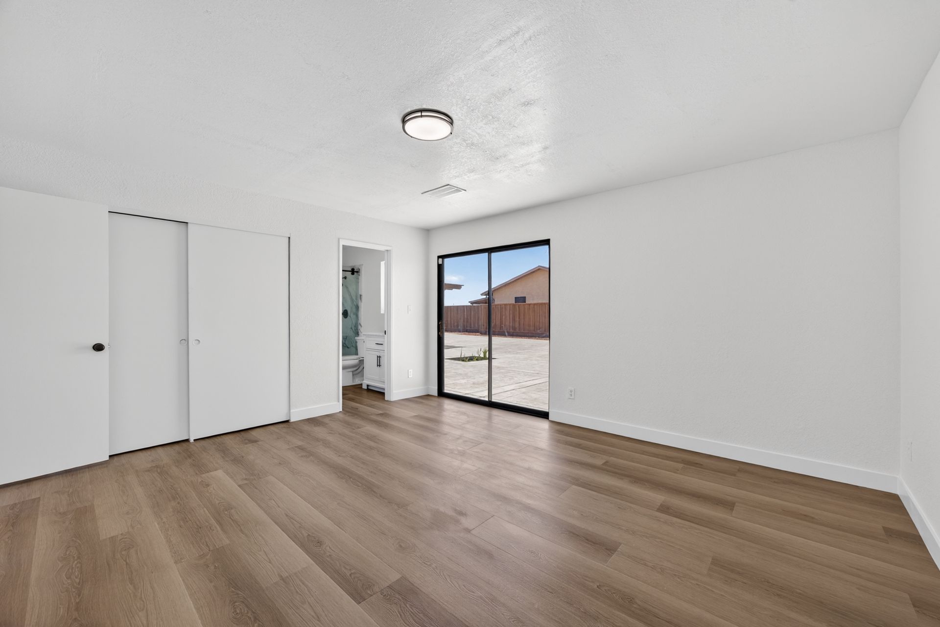 A third bedroom with sliding glass doors opening directly onto the back patio and the rear yard beyond